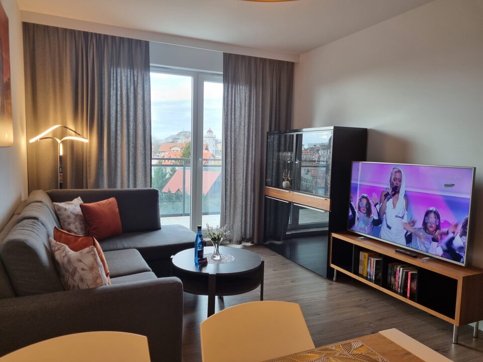 Stue med hjørnesofa og stort tv – Lejlighed Bel Mare, Międzyzdroje